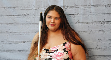 Avah Orellana a member of the New Hampshire affiliate smiles with her long white cane.